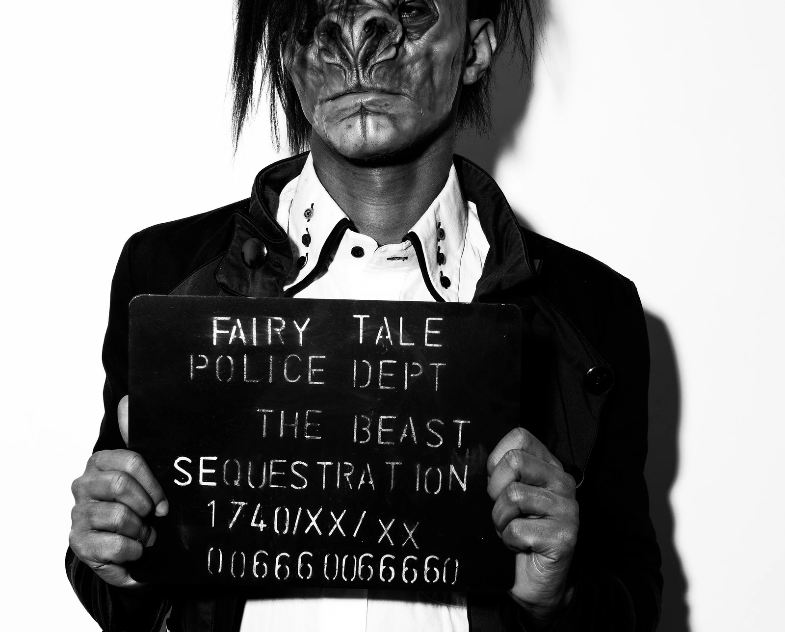 Black-and-white character portrait holding a Fairy Tale Police Department board